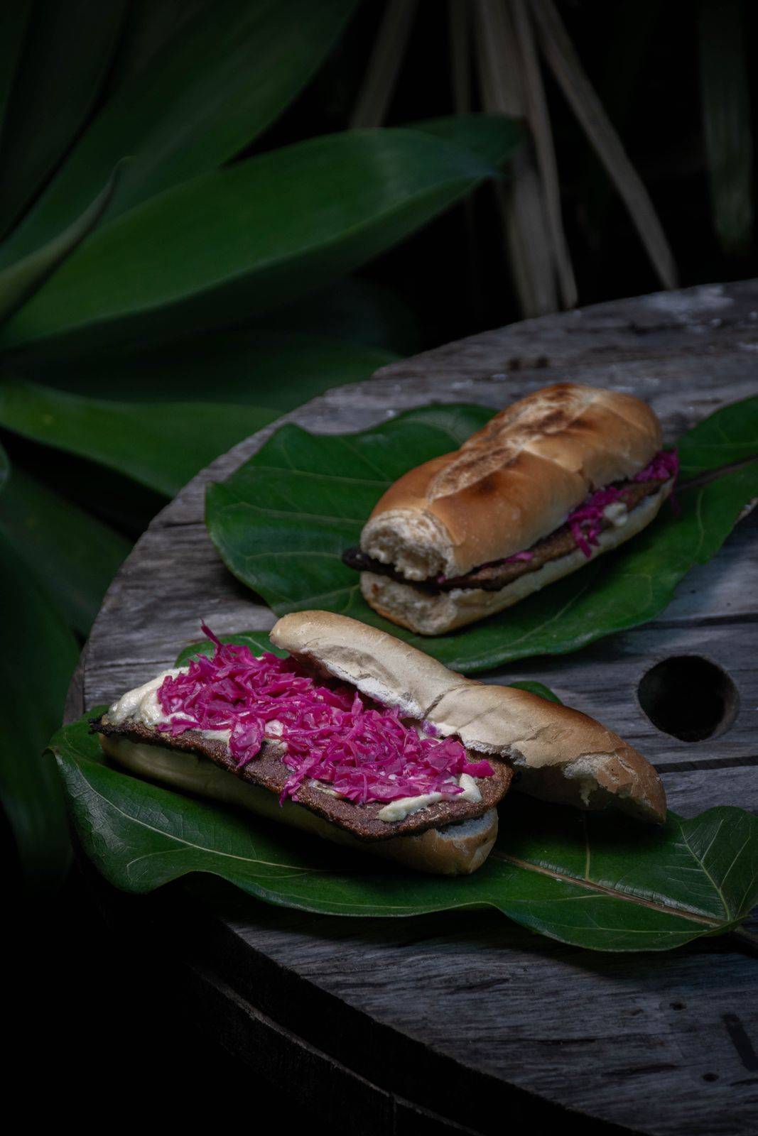 Dos sándwiches de bife de seitán con repollo morado sobre hojas verdes